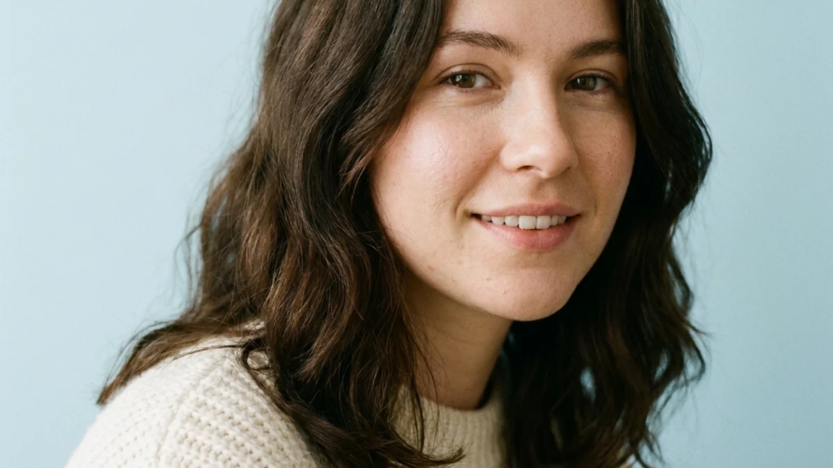 Editorial portrait of a young adult woman against a pale blue studio backdrop